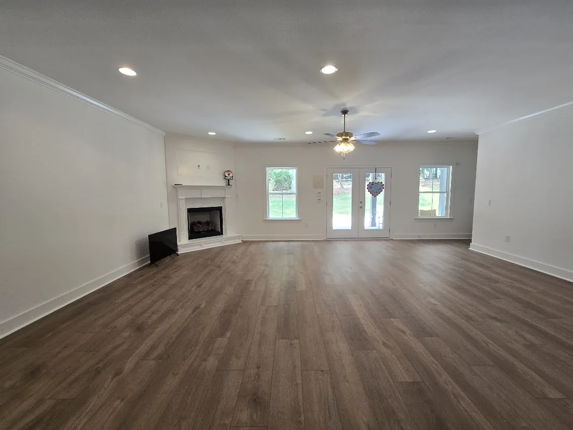 Unfurnished living room with fireplace, natural light, and doors facing the backyard